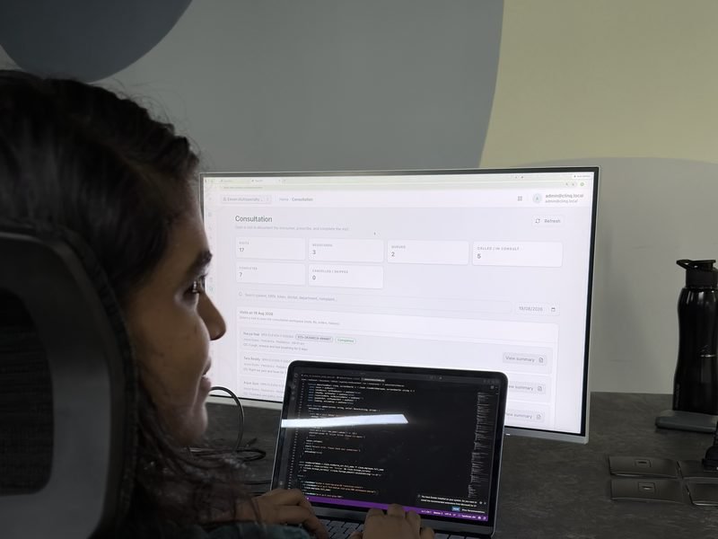 An Expericia engineer building a feature: code on the laptop, the application on the monitor