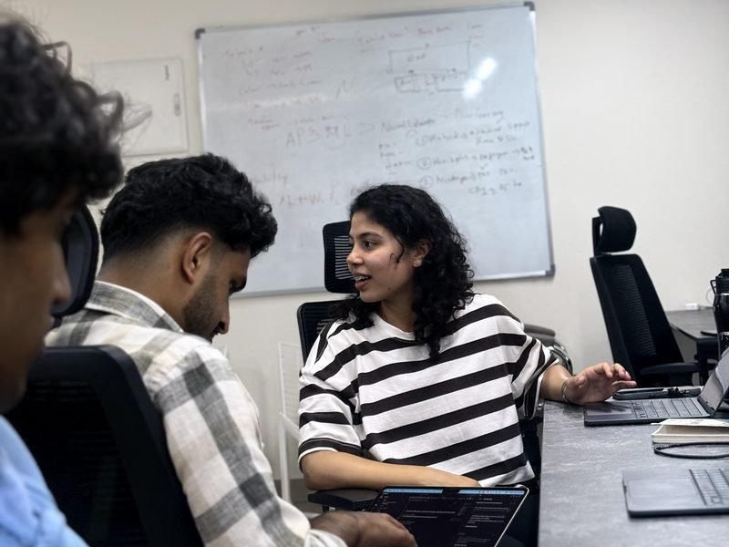 Three engineers working through a problem, the whiteboard behind them