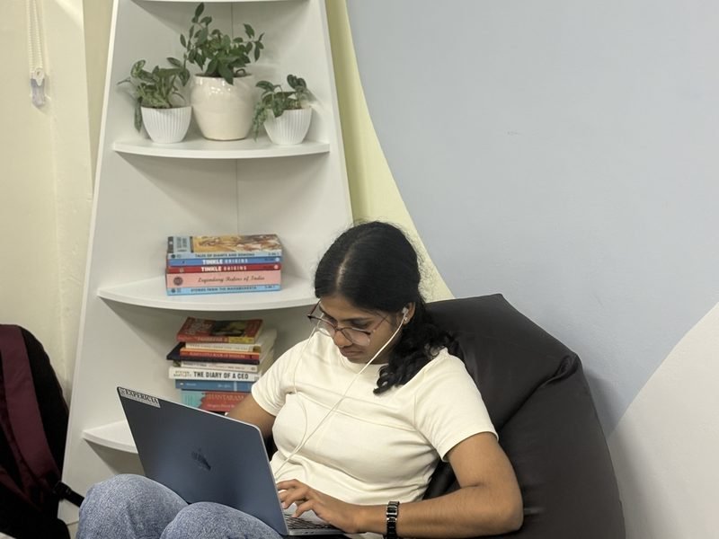 An engineer working from the bean-bag corner by the bookshelf