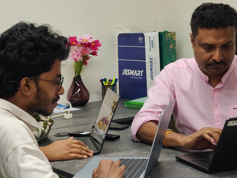 Two colleagues comparing notes on their laptops at the Kochi office
