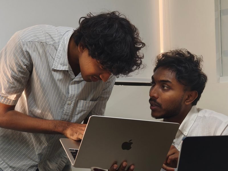 Two Expericia engineers working through a problem over one laptop