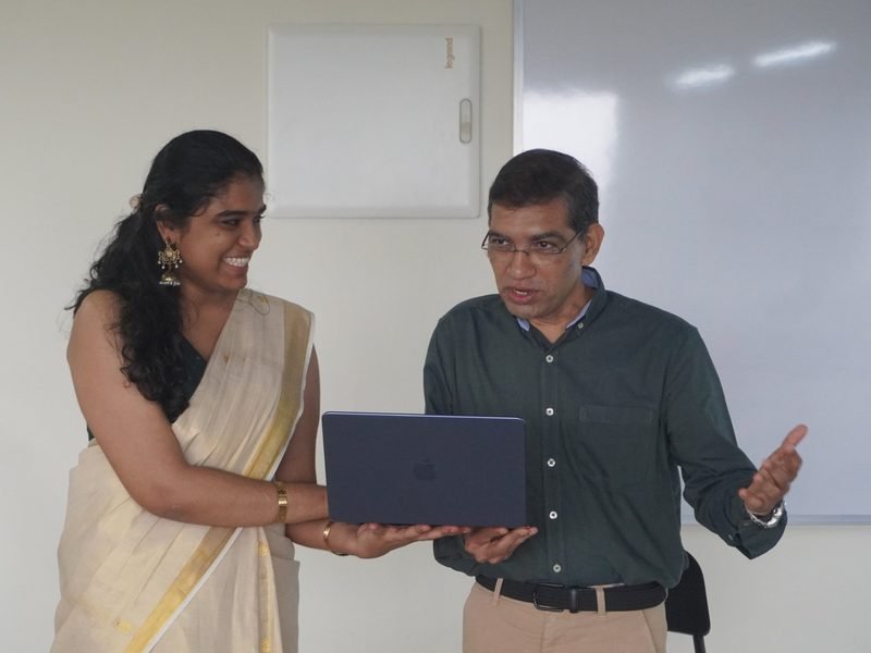 A senior architect and an engineer walking through a build together on one laptop at the Kochi office