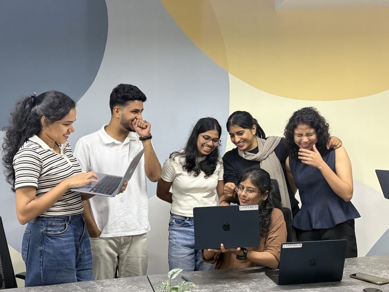 The team gathered around one laptop at the Kochi office, laughing at something on screen