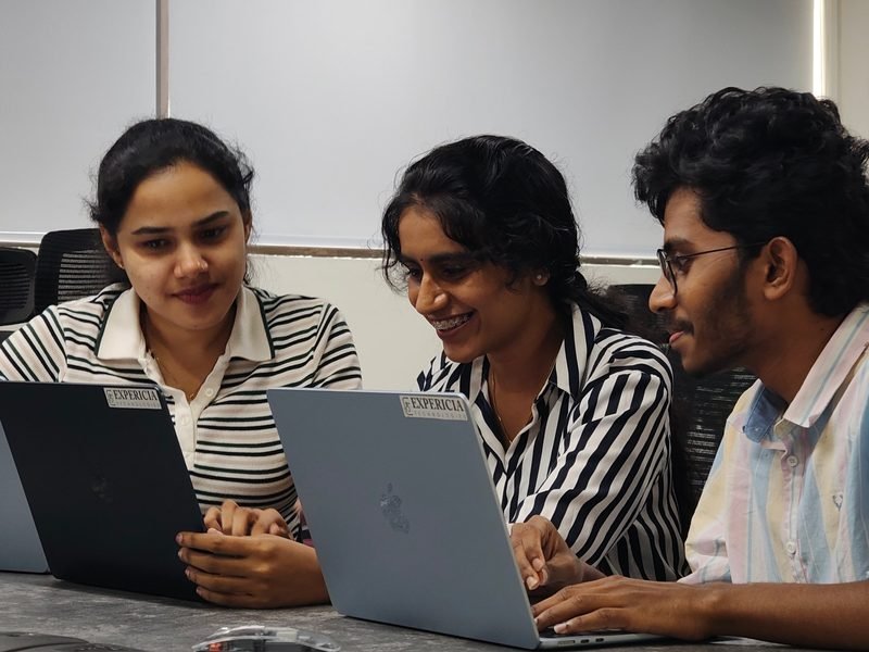 Three Expericia engineers working through a problem together on their laptops